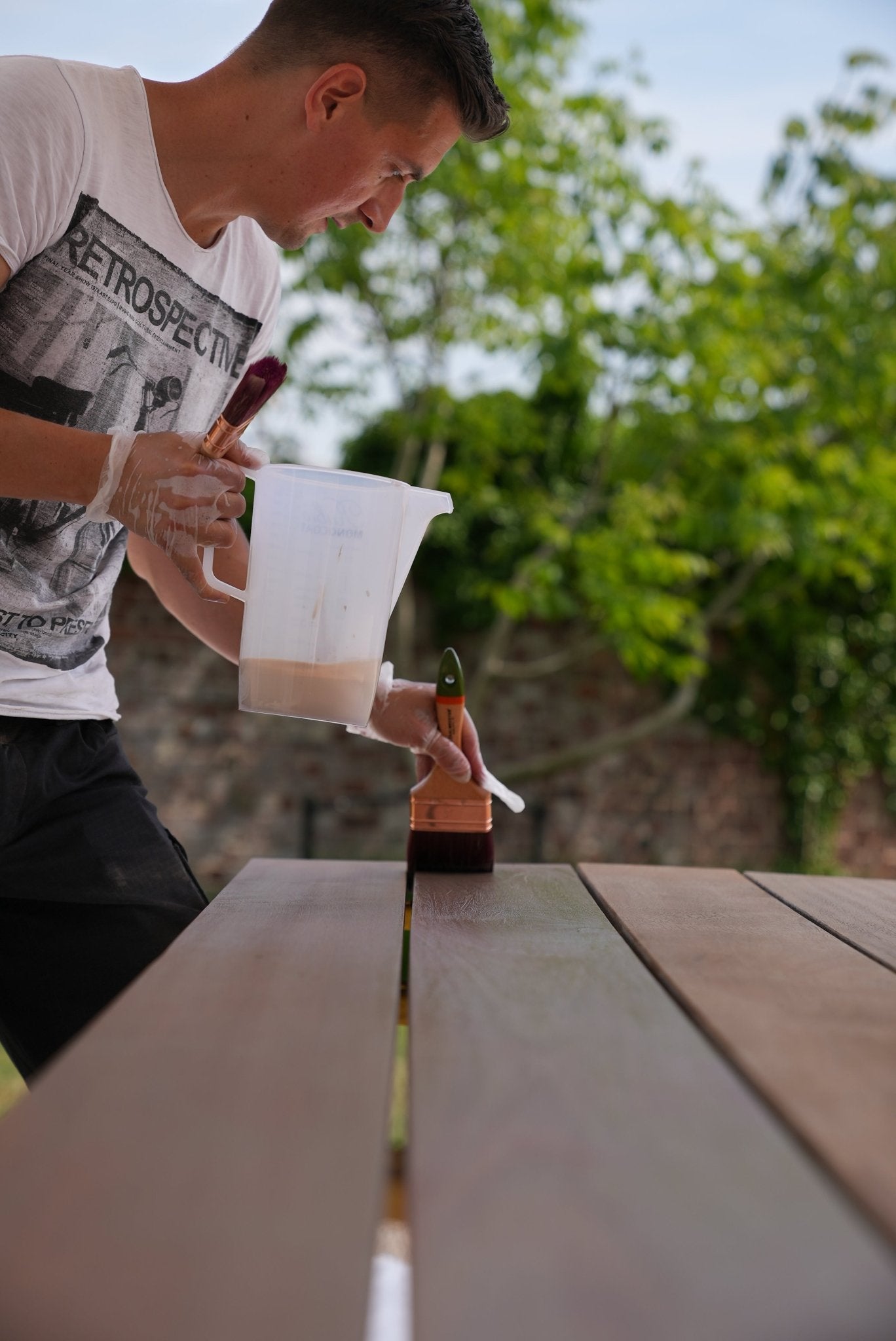 Person applying a Rubio Monocoat wood protetcion to a wooden surface outdoors.